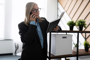 Middle aged older business woman in the office talking on a mobile phone