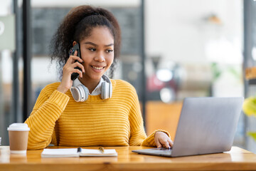 Portrait of an African businesswoman smiling cheerfully and talking on the phone with a colleague...