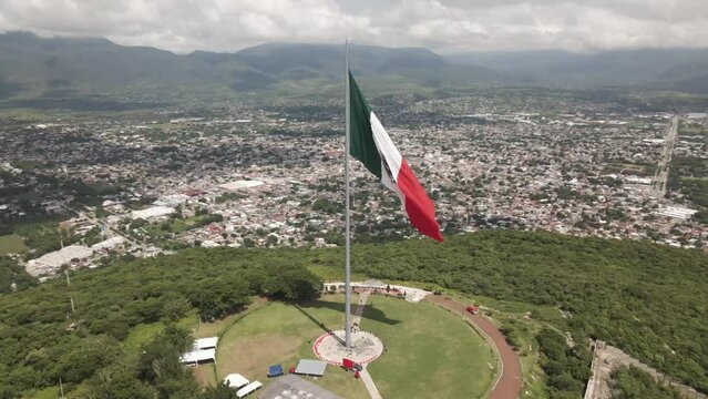 Slow aerial view of the waving Mexico Independence Declaration flag above Iguala