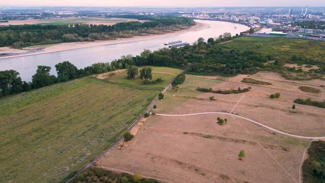 Aerial drone flyover the brown dry fields along the river Rhein in Cologne, Germany near Godorf - two inland cargos vessels on the river in the distance 2022