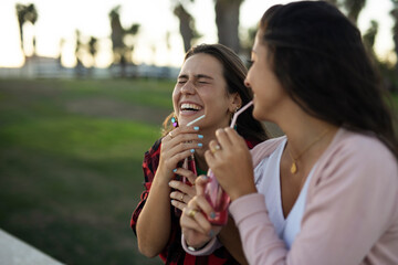 A beautiful lesbian young couple embraces. Girls drinking juice. LGBT community.