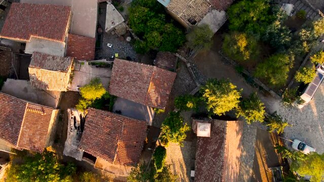 Aerial sunset drone footage of traditional deserted medieval countryside village Phicardou (Fikardou), Nicosia, Cyprus. Reveal scene of old abandoned ceramic tiled roof houses and church from above.