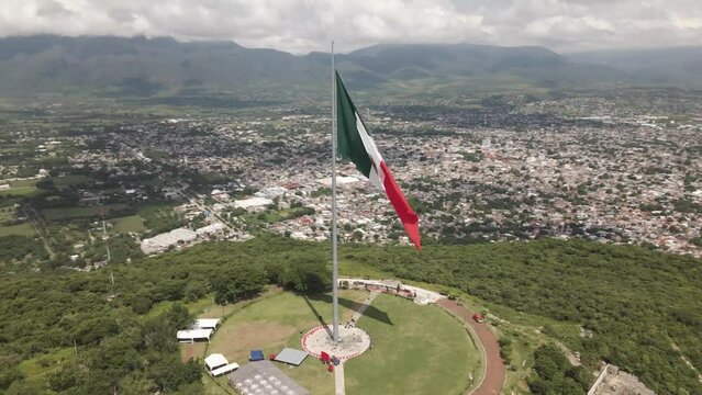 Aerial spin around Mexican flag over the city of Iguala in the state of Guerrero