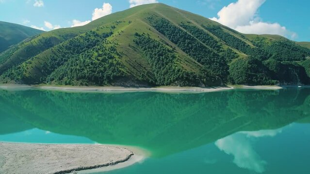 Aerial over lake Kezenoy-am with turquoise water and tall mountains around. Stunning scenery in highlands of Chechen Republic, Russia
