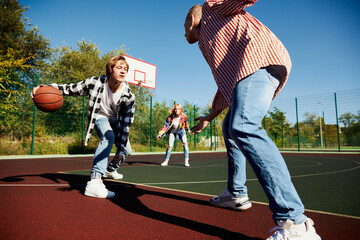 Young boys and girls, students bonding outdoors to play street basketball. Teens wearing casual style clothes. Youth, sport, energy, motion, active lifestyle