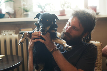 Cute love between a man and a dog; rastafarian dreadlocks man holding his dog, petting and hugging...