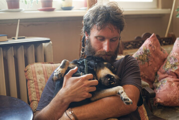 Cute love between a man and a dog; rastafarian dreadlocks man holding his dog, petting and hugging...