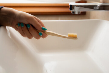 Cepillo de dientes sostenido por mano de chica joven con las u&ntilde;as pintadas