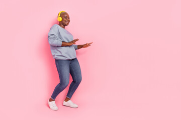 Full length photo of cheerful girl enjoy listen music dance empty space isolated on pink color background