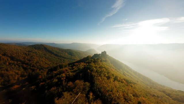 Dynamic ascending shot of wachauer hills, revealing medieval Aggstein covered in evening lights.