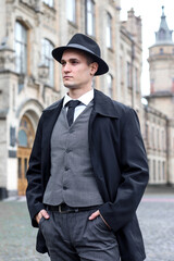 Men's photo shoot in a classic plaid suit and a hat against the backdrop of an old building.