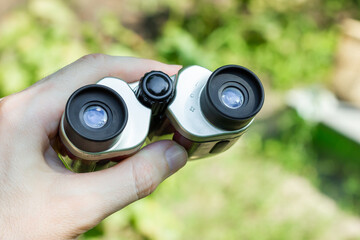 Small hiking binoculars. Binoculars in hand. Watch through binoculars