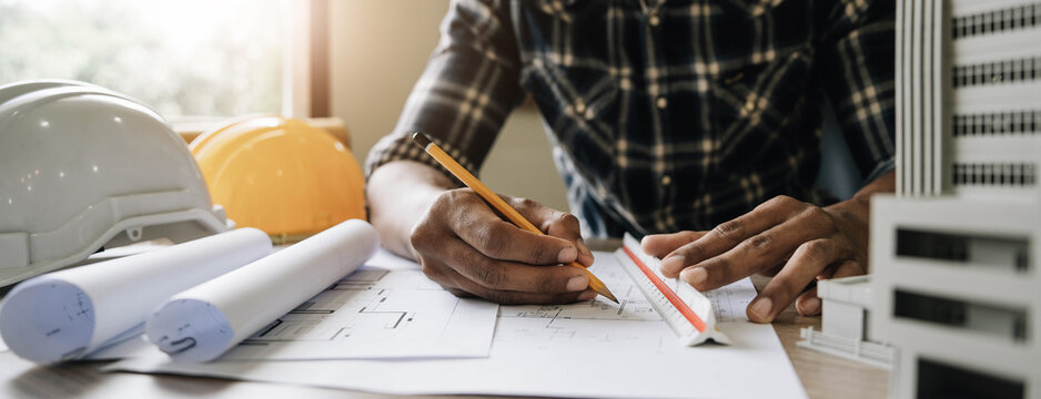 Image Of Engineer Drawing A Blue Print Design Building Or House, An Engineer Workplace With Blueprints, Pencil, Protractor And Safety Helmet, Industry Concept