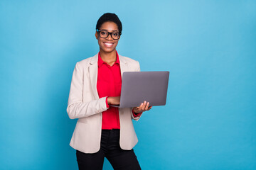 Portrait of attractive cheerful skilled expert developing web project using laptop isolated over bright blue color background