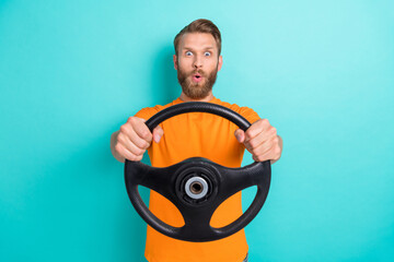Photo of impressed young man pouted lips arms hold steering wheel isolated on emerald color background
