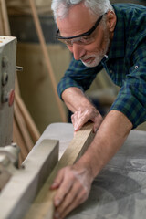 Mature carpenter working in a worshop and looking involved