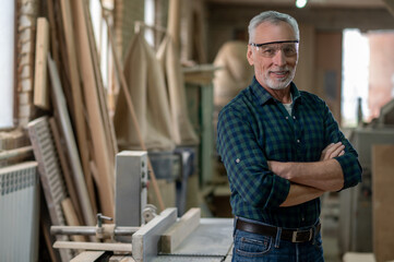 Mature man standing in a workshop and looking confident