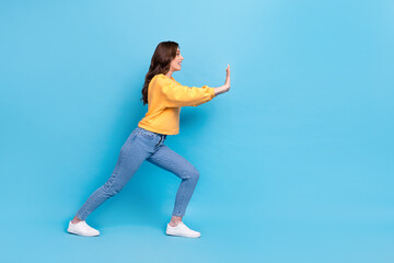 Full length photo of funny pretty girl dressed yellow pullover pulling huge empty space isolated...