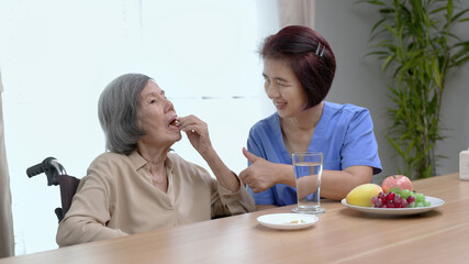 Obraz na płótnie Canvas Caregiver entering fish oil to elderly woman at retirement house.