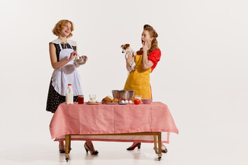 Portrait of two elegant, stylish women doing cooking together and discussing rumors isolated over...