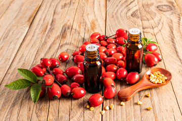 two medical bottles with a dropper with essential oil of rosehip seeds or natural essence for self-care. therapeutic effect. wooden background.