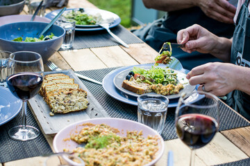 BBQ Outdoor with food preparations. People eating and dining outdoor. Lots of vegetables, fish, and meat.