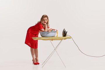 Portrait of beautiful woman doing ironing after washing isolated on white background. Feeling...
