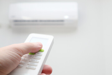Man's hand using remote controler. Hand holding remote and adjusting temperature of air conditioner...