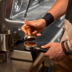 Close-up of hand Barista cafe making coffee with manual presses ground coffee using tamper at the coffee shop