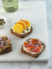 assorted toasts with dark rye bread, herrings, smoked salmon and capers. copy space. Vertical