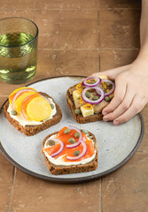 kid hand pick up toast with dark rye bread, herrings, smoked salmon and capers. copy space. Vertical