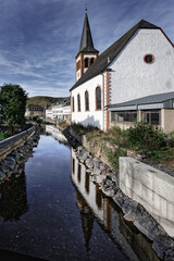 the romantic evangelical trinity church reflected in the urft river in the german eifel town gemuend