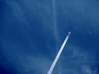 Flugzeug mit Kondensstreifen hoch am Himmel
