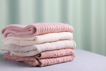 A stack of warm knitted sweaters on a gray background. Selective focus