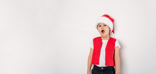 Portrait of singing boy in red Santa Claus hat isolated on white background. Cute 5 year singer child. Copy space. Banner. Concept of holiday music. Creative hobby. Sing lessons gift certificate. Wow