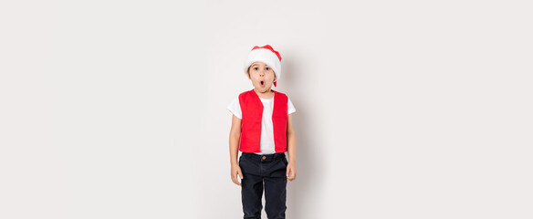 Portrait of singing boy in red Santa Claus hat isolated on white background. Cute 5 year singer...