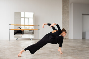 Modern female dancer in black outfit practices in a dance studio - 541452425