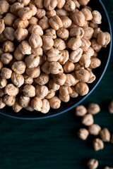 Dried chickpeas in a wooden bowl on a wooden background.