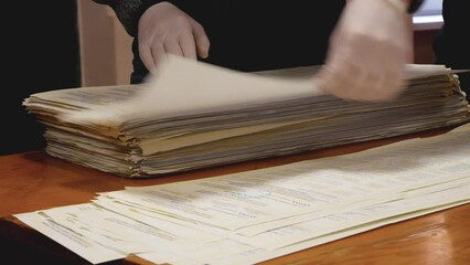 Unrecognizable hands in white gloves recount ballots with votes at the polling station during the election. The concept of democratic voting in elections. Expression of will during elections. 2022 USA