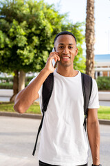 Obraz premium Young african american man smiling happy talking on the smartphone at street of city.