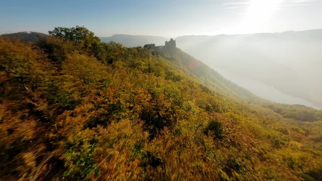 FPV approaching beautiful Aggstein, passing a stone formation on green wachauer hills in autmn light.