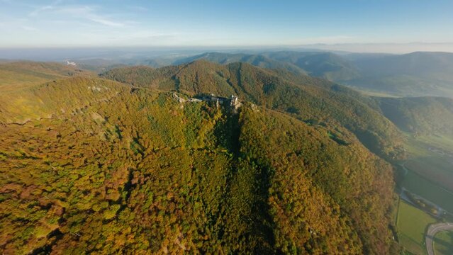FPV passing over Wachau valley, slowly approaching painterly Aggstein in warm lighting.