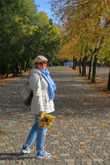Fototapeta premium Walk in the autumn park with a bouquet of yellow leaves.
