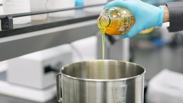 Pouring fresh yellow lubrication oil into a bowl and measure the weight. Prepare oil for making grease in the laboratory. Batch trial and experiment. Industrial and manufacturing concept