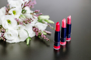 Obraz na płótnie Canvas Set of colored lipsticks. Concept of cosmetics and care. Beautiful flowers. Copy space.