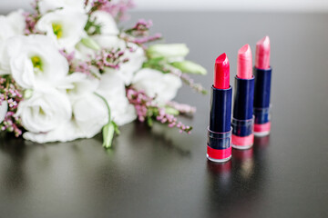 Obraz na płótnie Canvas Set of colored lipsticks. Concept of cosmetics and care. Beautiful flowers. Copy space.