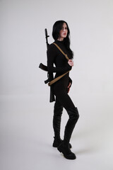 Beautiful slender brunette woman in black clothes with assault rifle