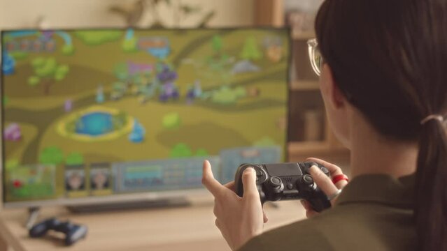 Rear view shot of girl playing rpg video game with controller at home during leisure time