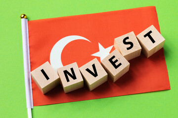 Wooden cubes with text and a flag on a colored background, a concept on the theme of investment from Turkey