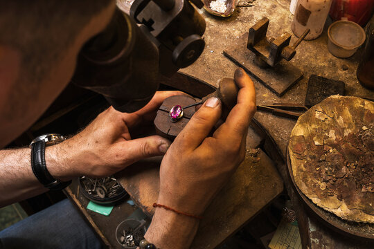 The jeweler takes out a stone from the setting of a gold ring, repairing jewelry